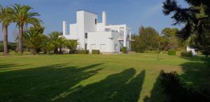 a large white house with palm trees in front of it at Finca Campo Viejo in Isla Cristina