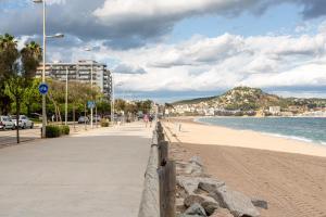 a sandy beach with a fence and the ocean at Apartamento Costa Brava in Blanes