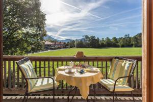 a table and chairs on a porch with a view of a field at Alpen Chalet Alte Talstation in Lenggries