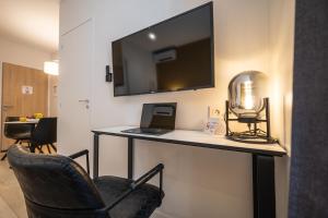 a room with a desk with a laptop and a television at Five Resort Cholet Centre in Cholet