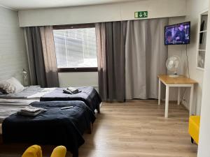 a hotel room with two beds and a tv at Kangaskartano Yksiö in Keitelepohja