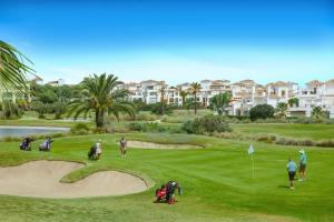 a group of people playing golf on a golf course at Townhouse overlooking golf course in Las Armeras