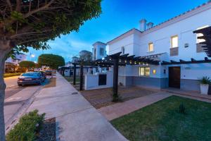 a white house with a car parked on the street at Townhouse overlooking golf course in Las Armeras