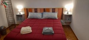 a bed with a red comforter and towels on it at B e B Beglia Alguer in Alghero