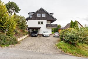 a house with two cars parked in the driveway at Ferienwohnung Kleine Auszeit in Schmallenberg