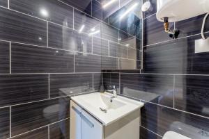 a bathroom with a white sink and black tiles at Canto Cigalo Rdc 1 in Robion en Luberon +13 photos