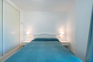 a white bedroom with a blue bed with two night stands at Kiko Las Americas in Isla Cristina +27 photos
