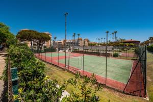 two tennis courts with palm trees and buildings at Kiko Las Americas in Isla Cristina