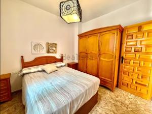 a bedroom with a bed and a wooden cabinet at Apartamento Rey Melchor in Trevélez
