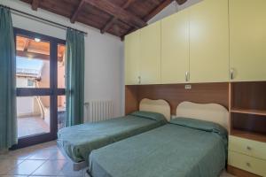 a bedroom with two beds and a sliding glass door at Quadrilocale 800mt dal mare in San Teodoro