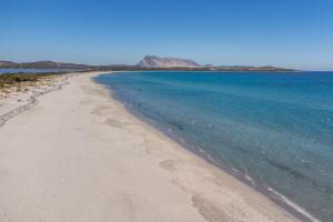 a beach with blue water and mountains in the background at Quadrilocale 800mt dal mare in San Teodoro