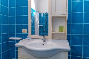 a blue tiled bathroom with a sink and a mirror at Quadrilocale 800mt dal mare in San Teodoro +12 photos