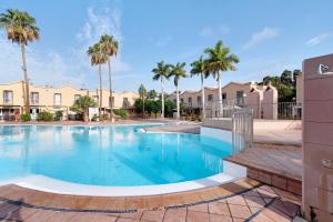 a large swimming pool with palm trees and houses at Place Oasis Green Luxury Pool in Maspalomas