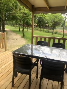 a table and chairs on a porch with a view of a park at Mobilehome Riviera avec terrasse 47 in Saint-Gervais