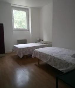 two beds in a white room with a window at Apt T3 - 3 Min du Futuroscope in Chasseneuil-du-Poitou