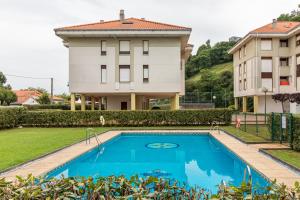 a house with a swimming pool in front of a building at Apartamento La Ribera in Suances