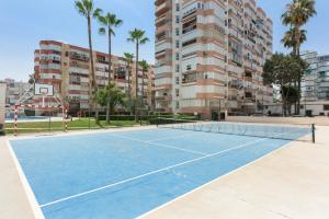 a tennis court in front of a building with palm trees at Apartamento Lucía in Torre del Mar