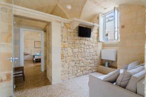 a living room with a couch and a tv on a stone wall at Corte Cochlea La Curte Suite per 4 in Cannole