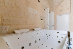 a white bath tub in a room with a stone wall at Corte Cochlea La Curte Suite per 4 in Cannole