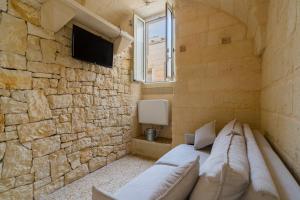 a room with a couch and a stone wall at Corte Cochlea La Curte Suite per 4 in Cannole +17 photos