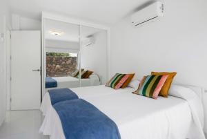 a white bedroom with two beds with blue pillows at Noray 2 in La Santa