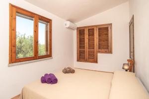 a bedroom with a bed and two purple slippers at Sardegna Budoni giardino e Jacuzzi in Budoni