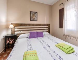 a bedroom with a white bed with purple and green towels at El Paladin in Zufre