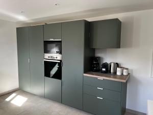 a kitchen with gray cabinets and a stove at La Buissonnière in Erckartswiller