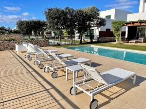 a row of lounge chairs next to a swimming pool at Casa da Lúa in Sant Lluis