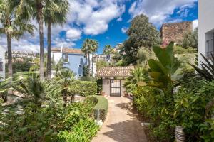 a house with a garden and palm trees at Beautiful penthouse with solarium in Benahavís