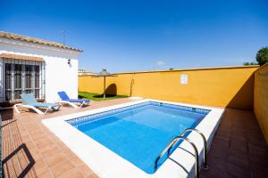 a swimming pool with two chairs and a house at Luisa 2 in Conil de la Frontera