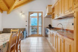a kitchen with wooden cabinets and a table with a counter at Agritur Sotto il Melo in Caldes