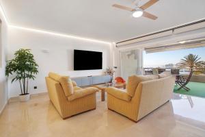 a living room with two chairs and a flat screen tv at Luxury in Puerto Marina in Benalmádena