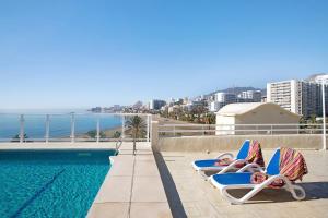 two people laying in lounge chairs next to a swimming pool at Luxury in Puerto Marina in Benalmádena