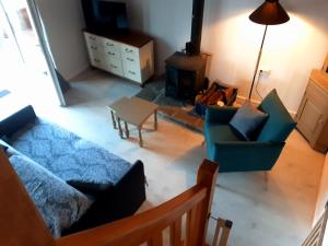 a living room with a couch and chairs and a stove at Le Gîte d’Ambre in Poullaouen