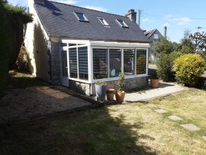 a screened in porch of a house with potted plants at Le Gîte d’Ambre in Poullaouen