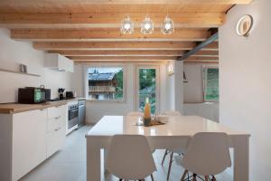a kitchen with white cabinets and a white table and chairs at Maison Millet Ozein in Aymavilles