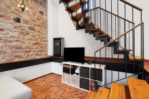 a living room with a staircase and a tv at Altes Kutschhaus in Gernsbach