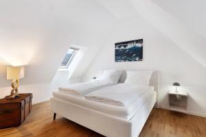 a white bedroom with a bed and a window at Altes Kutschhaus in Gernsbach