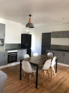 a kitchen with a wooden table and white chairs at Famille in La Bourboule