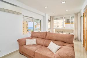 a living room with a brown couch and windows at Playa Algarrobo Costa in Algarrobo-Costa