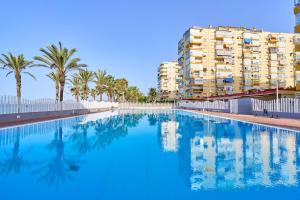 a swimming pool with palm trees and a building at Playa Algarrobo Costa in Algarrobo-Costa
