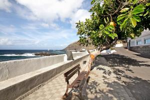a wooden bench sitting next to a wall and the ocean at Estudio La Morena in El Pris