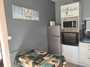 a small kitchen with a refrigerator and a microwave at La Maison Defanny - 1 in Muides-sur-Loire