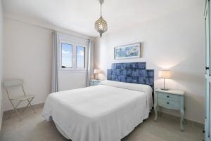 a white bedroom with a bed and a chair at Doña Amparo chipiona Playa de Regla in Chipiona