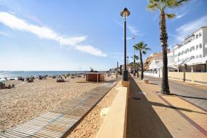 a sandy beach with palm trees and people on the beach at Doña Amparo chipiona Playa de Regla in Chipiona