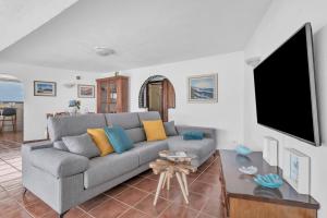 a living room with a gray couch and a flat screen tv at Villalmar in Famara