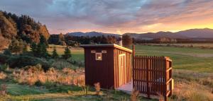 a small wooden outhouse in a field with a fence at Fantails Rest - Torokiki in Springfield