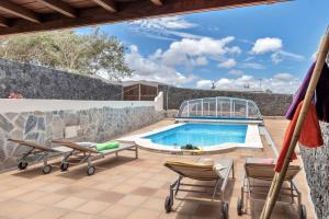 a patio with a swimming pool and two lawn chairs and a swimming pool at Villalmar in Famara