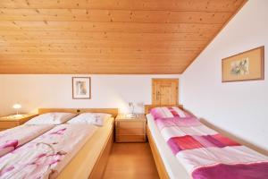 two beds in a room with wooden ceilings at Wieserhof Ferienwohnung Priml in Sarntal